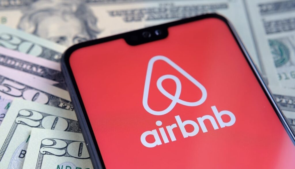 Phone with Airbnb app on stack of money