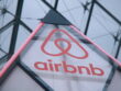 Airbnb logo on a triangular sign with a geometric metal framework in the background
