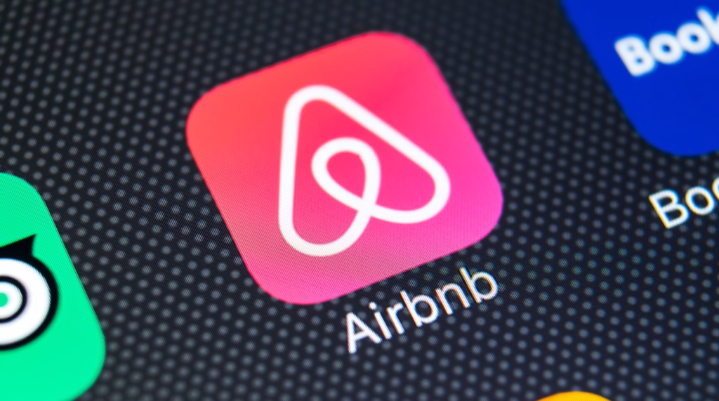 Airbnb app icon, a pink square with a stylized "A" logo, next to other app icons on a screen