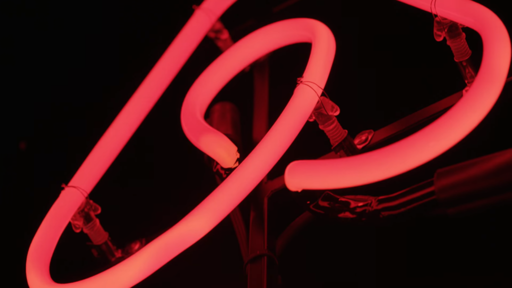 Close-up of intertwined neon tubes glowing in a vibrant red hue against a dark background