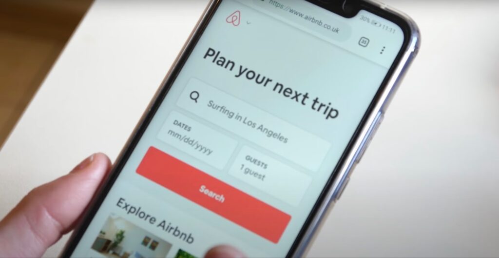 Hand holding smartphone with open Airbnb app
