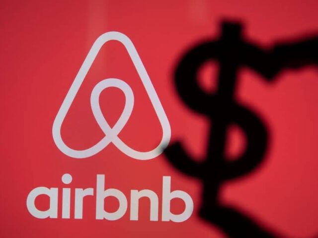 Hand holding dollar icon on background of Airbnb logo