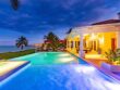 A luxurious beachfront villa with a pool at dusk in the Bahamas.