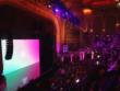 A grand theater lit in pink, with Airbnb's logo on screen and an eager audience awaiting the event